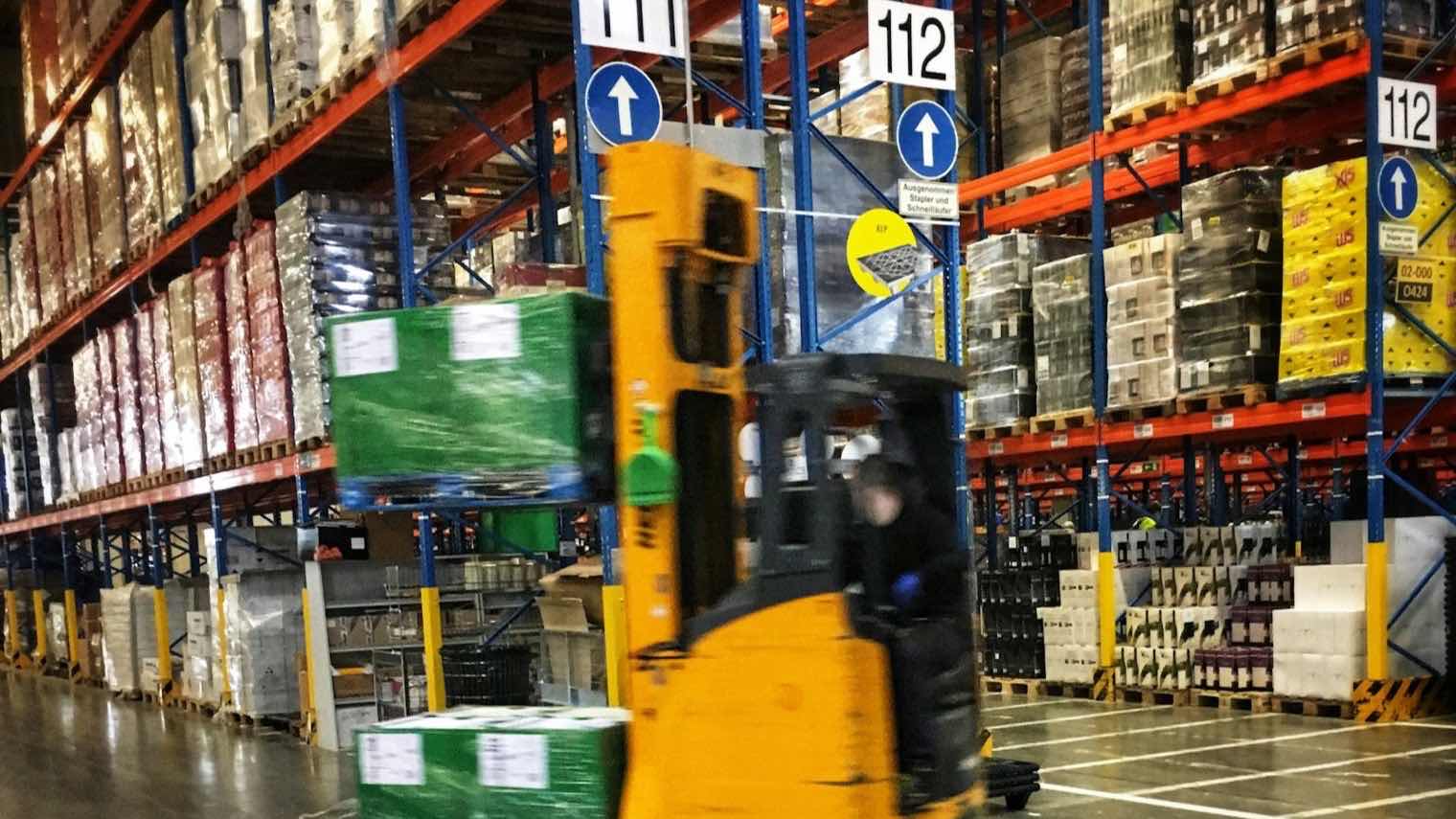 Ein Gabelstapler fährt durch ein Lager voller Paletten