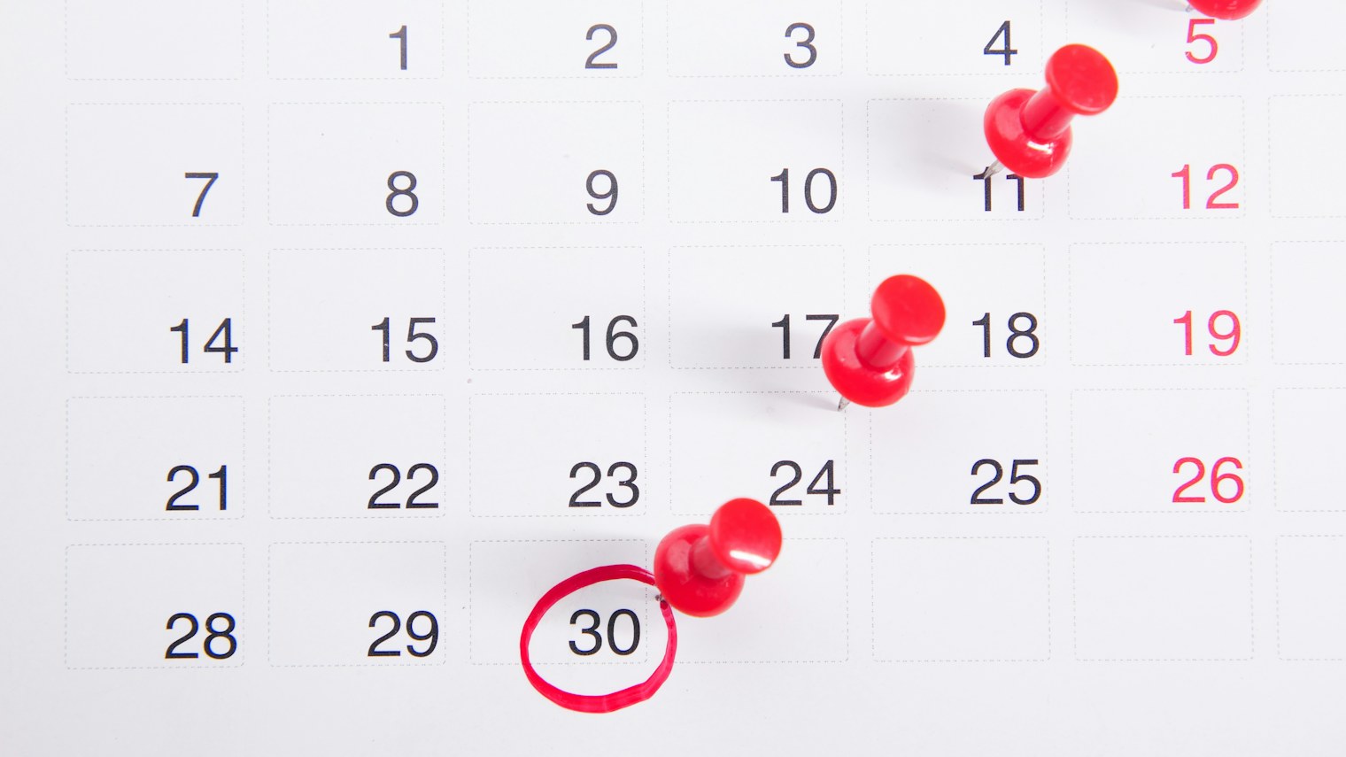 Wall calendar with red pins, one date circled in red